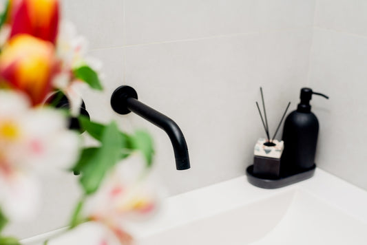 a bathroom sink with a soap dispenser and a vase of flowers